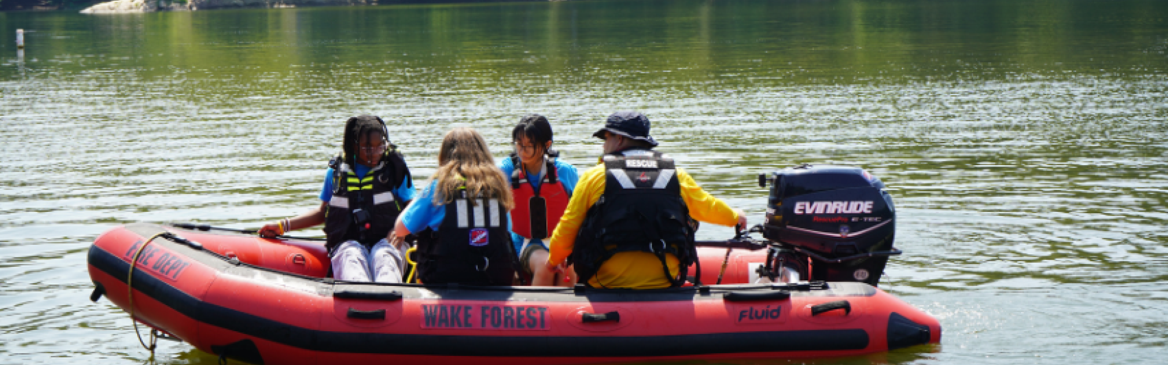 Three campers and an operator on a Wake Forest Search and Rescue boat in the water. 