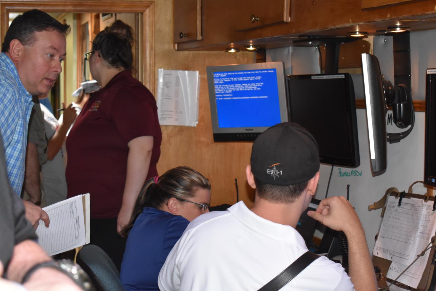 People sitting in front of three computer monitors