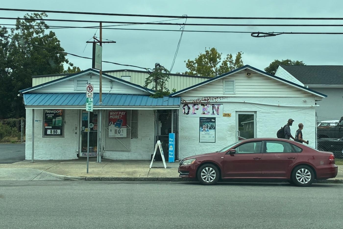 White building with light blue roof and a red car in front of it