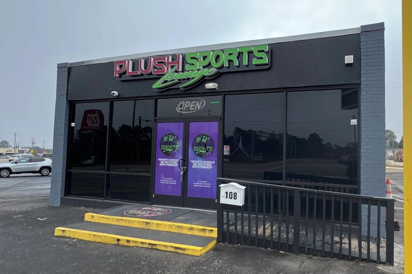 Plush Sports Lounge. Grey building with purple and green signage. 