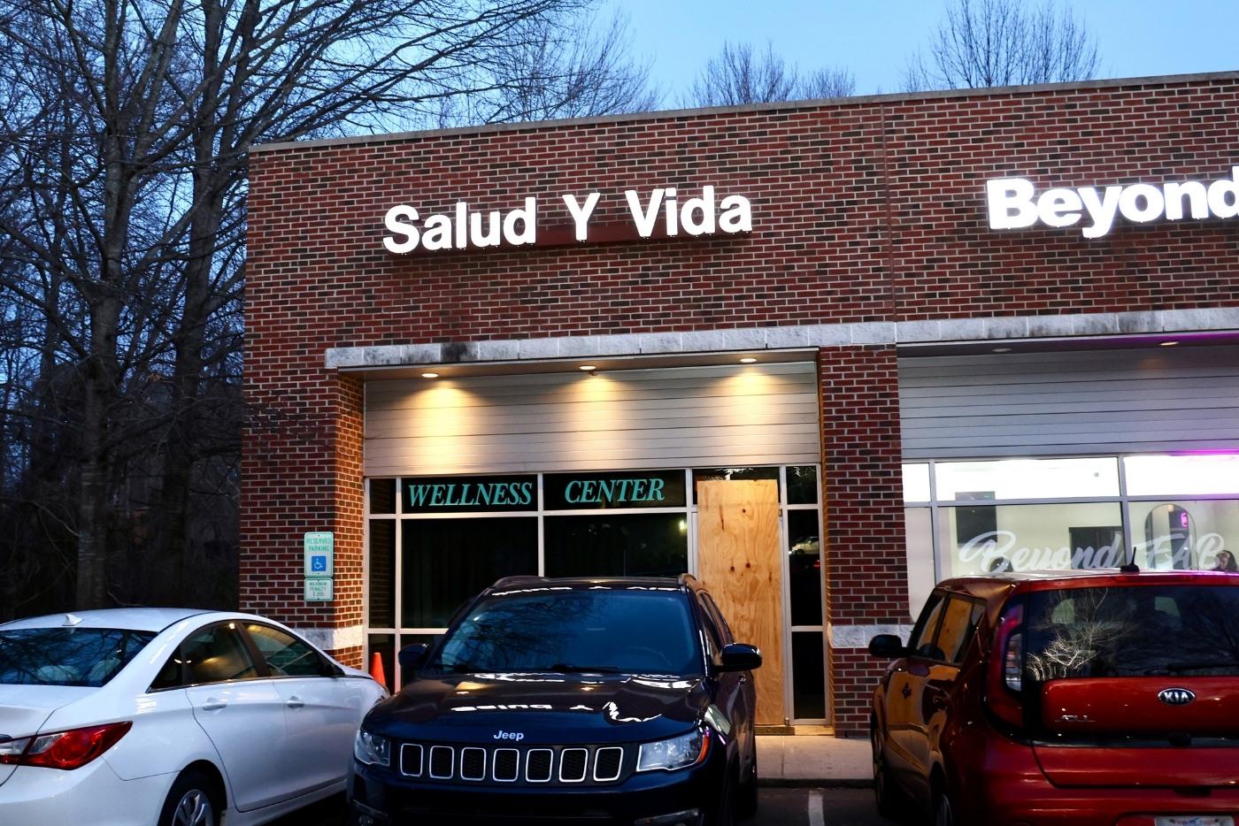 Brick building with dark windows and a plywood door at dusk