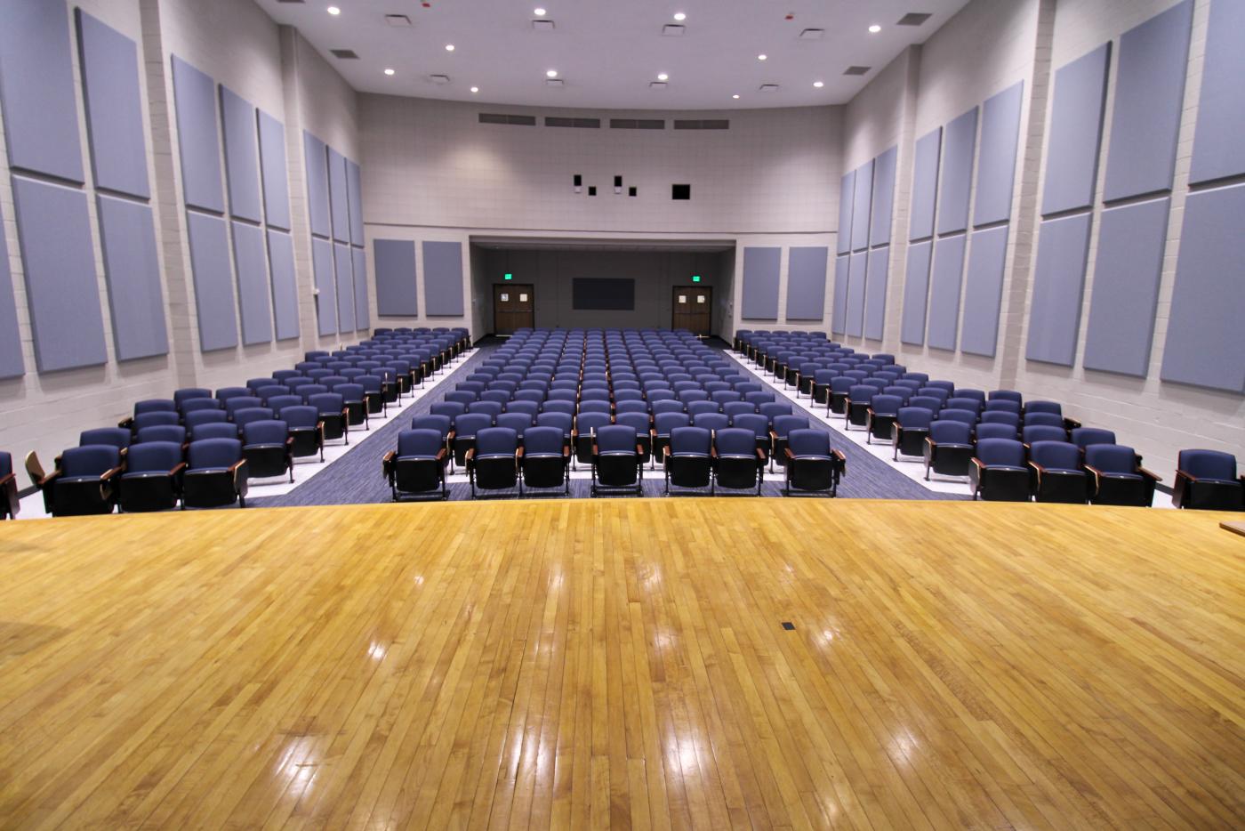 A stage with rows of blue seats in front.