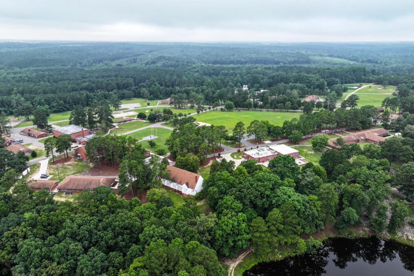 Aerial view of a campus with several buildings, trees and a lake.