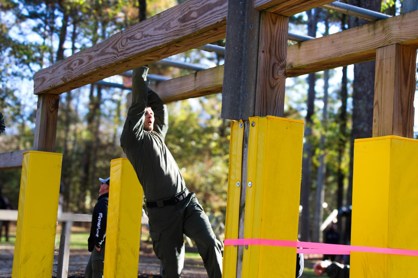 Person swinging on wooden monkey bars.
