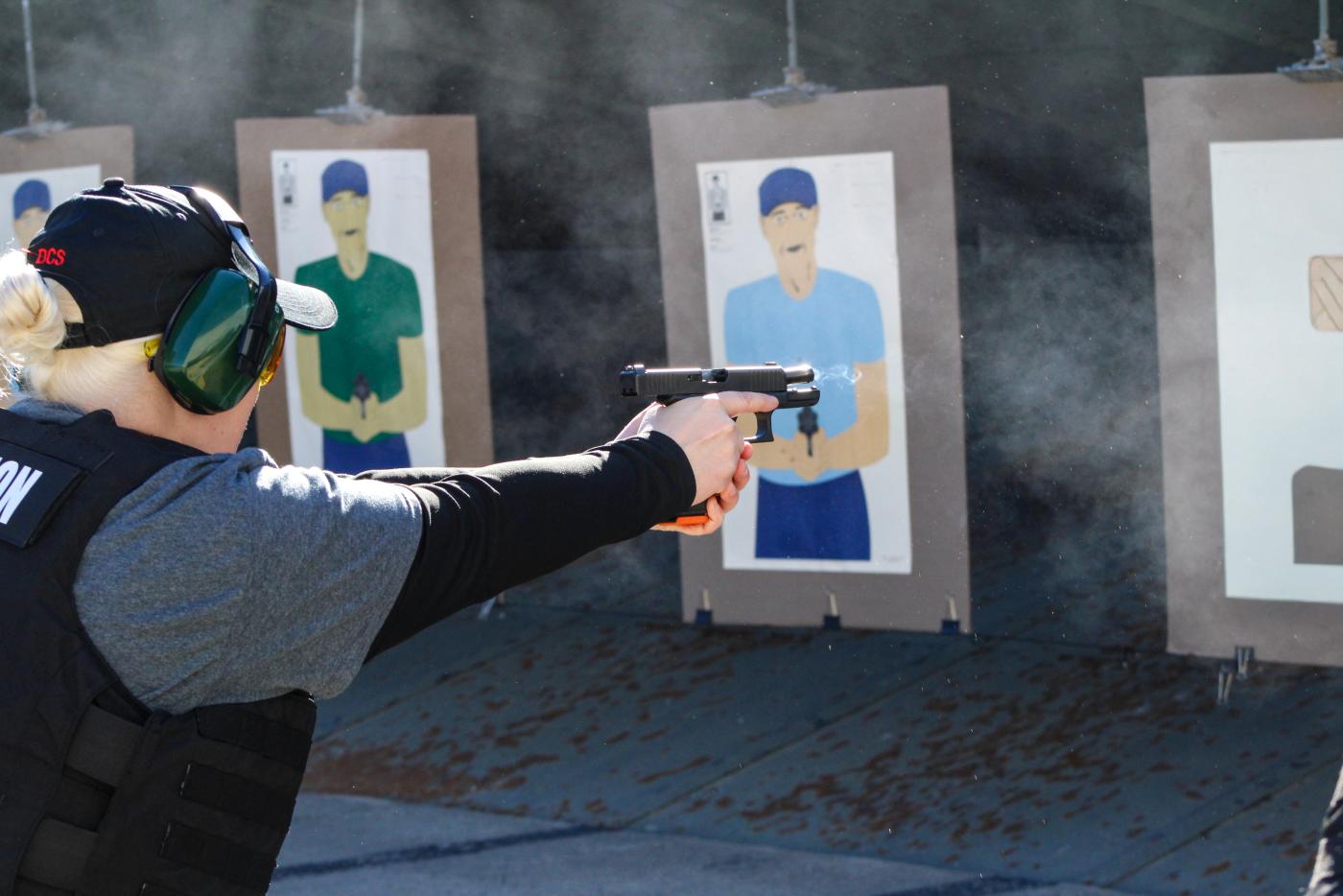 Female wearing protective ear covering shooting at a target downrange. 