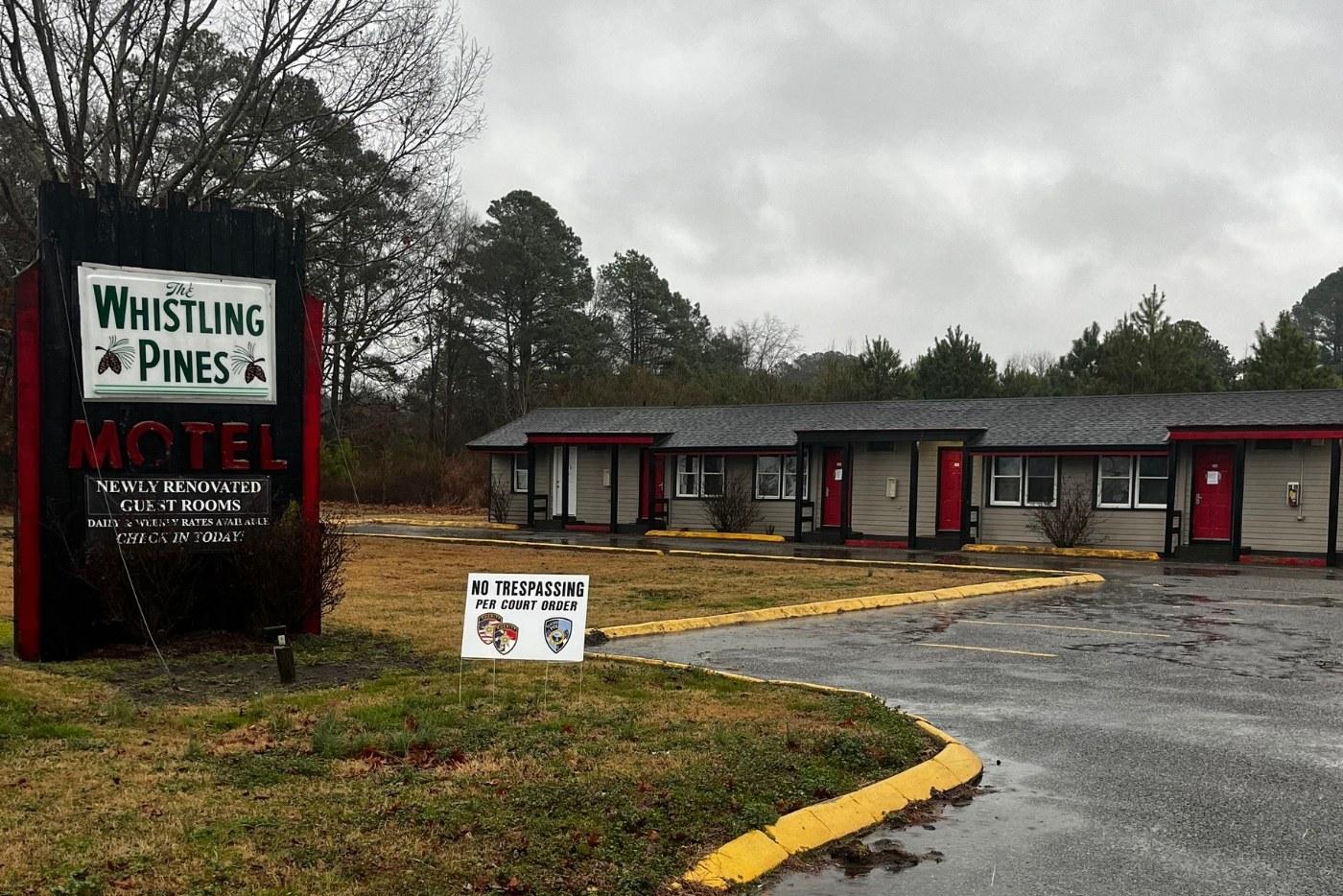 Grey motel with red doors with a sign that says no trespassiong 