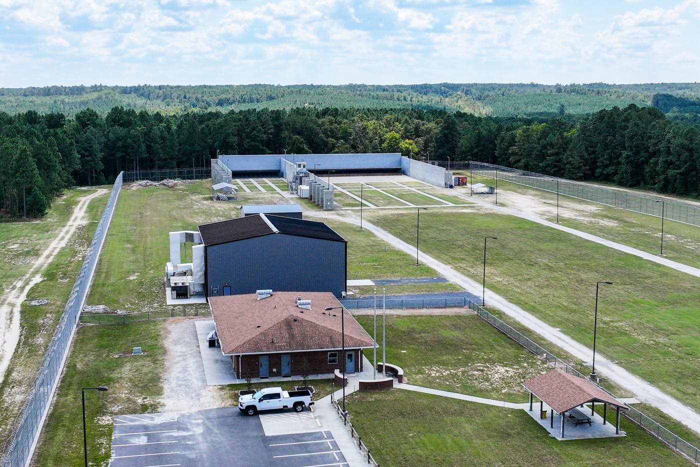 Overhead view of long field with two buildings and a parking lot on the side.