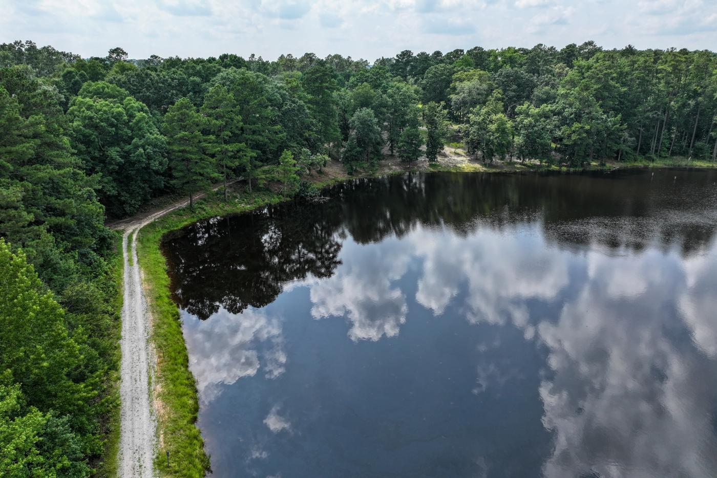 Lake with narrow path surrounding it. Trees boarder the lake area.