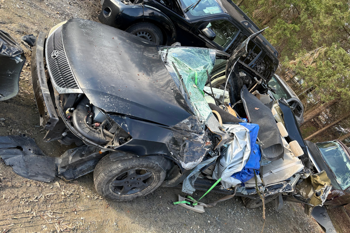 Wrecked black sedan in a tow lot