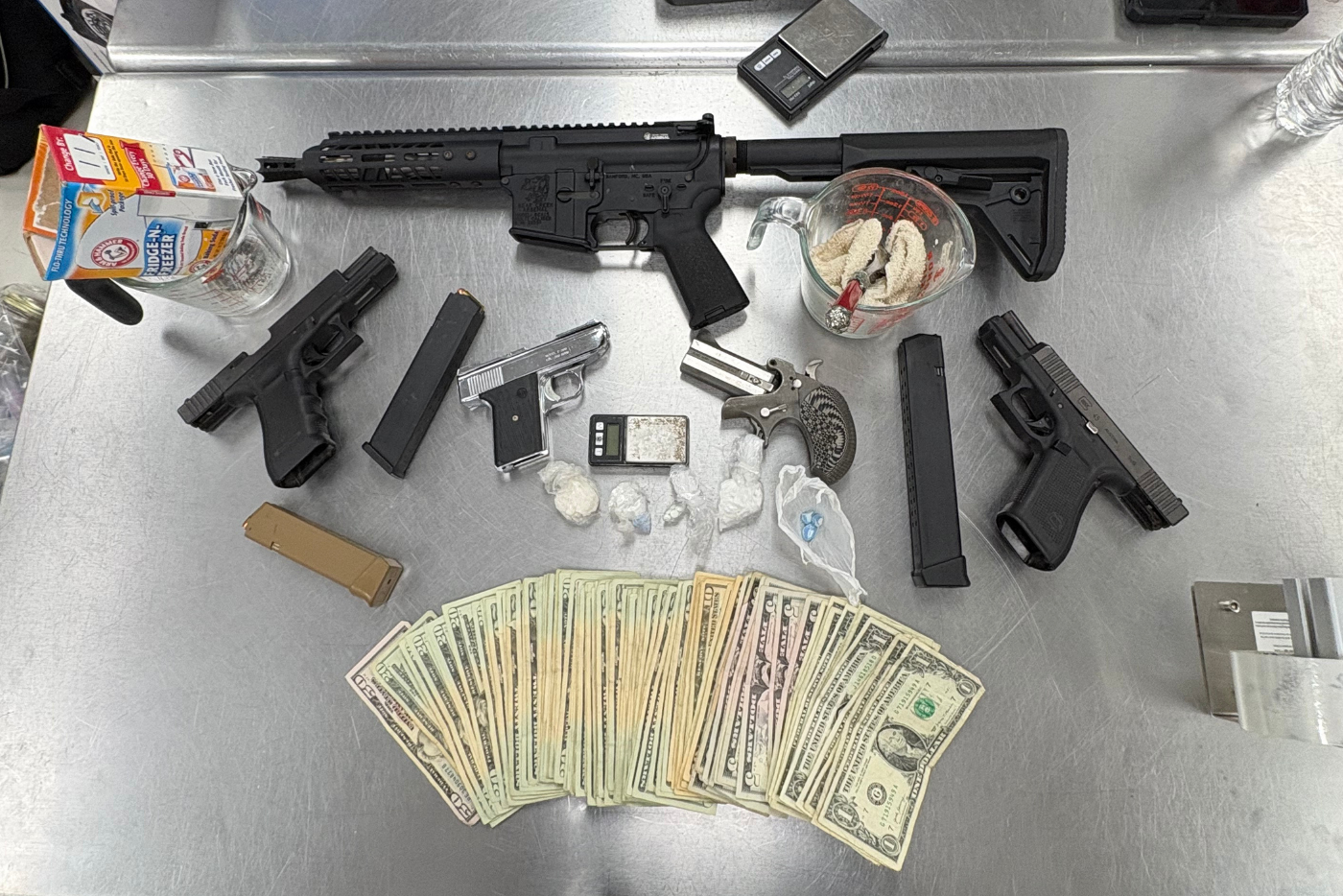 five firearms, including a short barrel riffle, various controlled substances and money laying on steel table