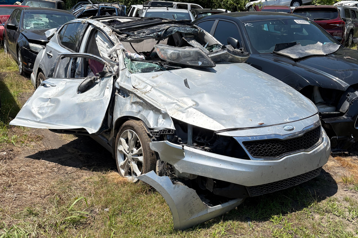 silver ford car with collision damage, a crushed roof, missing front bumper, and damaged side door