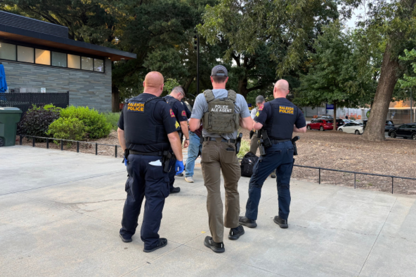 One ALE agent and RPD Officer standing with their back to the camera talking and wearing police protectige gear