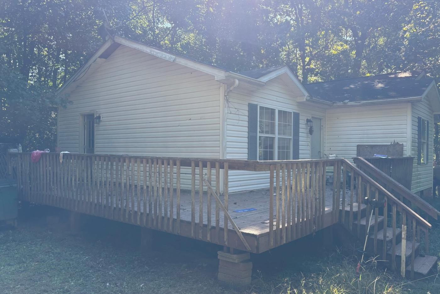 white house ranch style home with wooden wrap around porch and debris scattered across porch