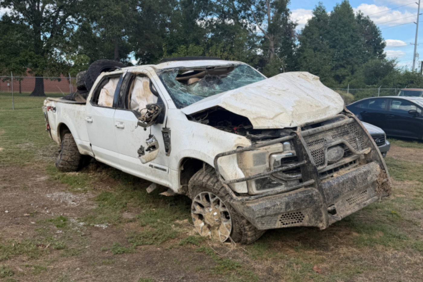 wrecked white ford truck with shattered windshield and airbags ejected out of all windows