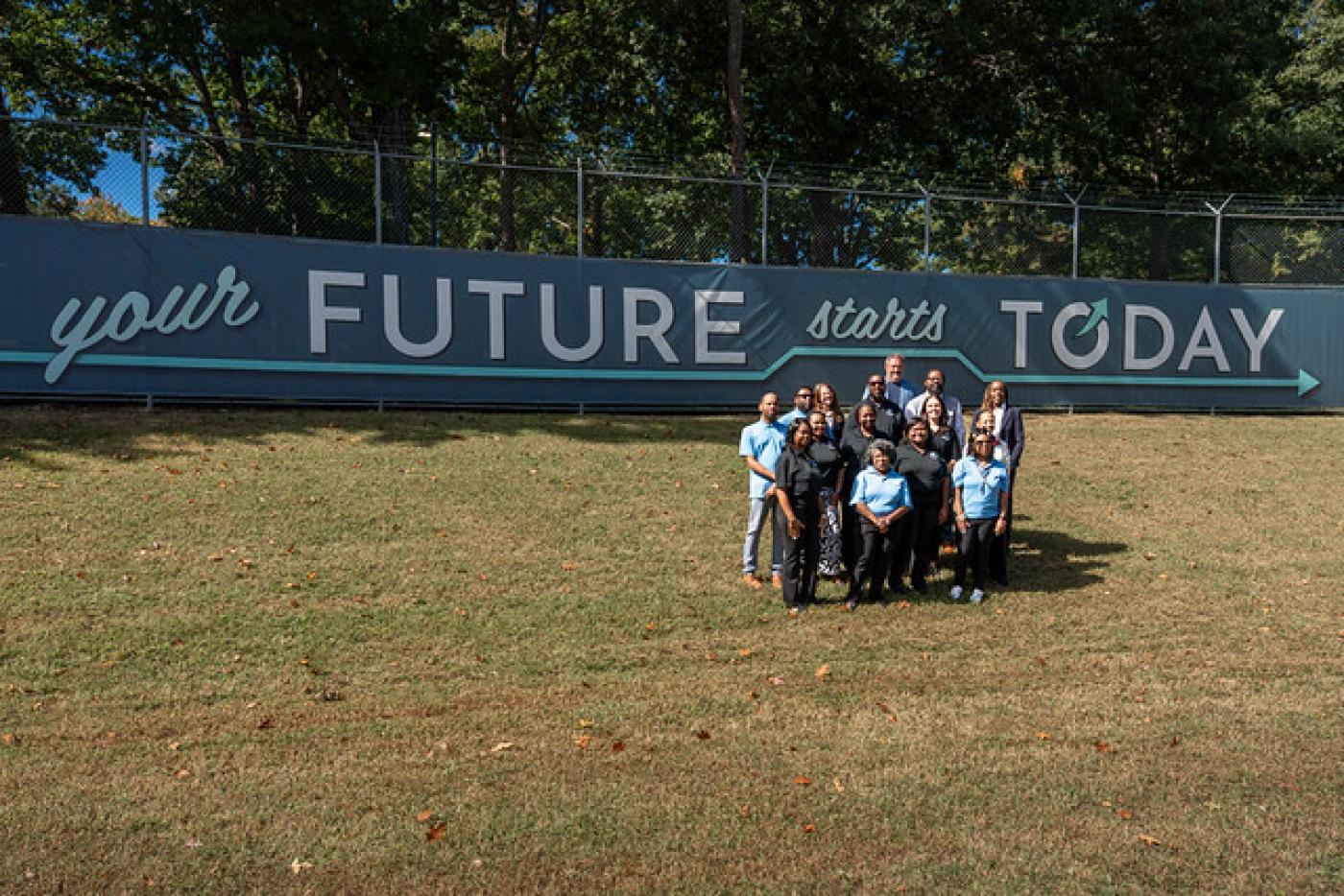 Group of people posed in front of a sign that says, "Your Future Starts Today"