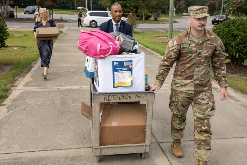 secretary and soldier unload school supplies