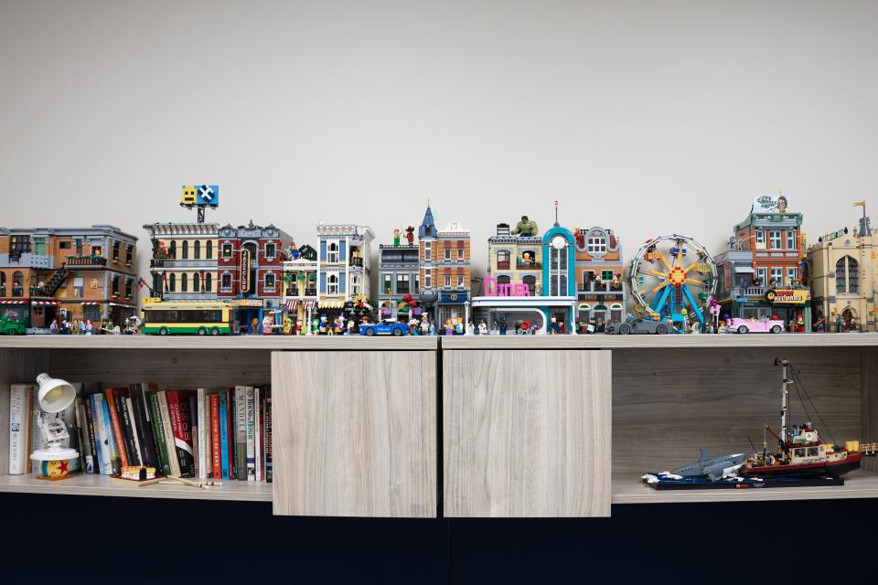 A collection of detailed LEGO modular buildings is displayed on top of a wooden cabinet.