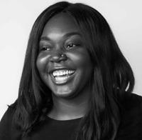 Woman with long black hair, wearing a black shirt, standing against a white background