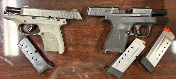two handguns with magazines laying on a wooden table