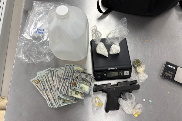 Moonshine, illegal controlled substances on a scale, cash and a firearm on a steel table