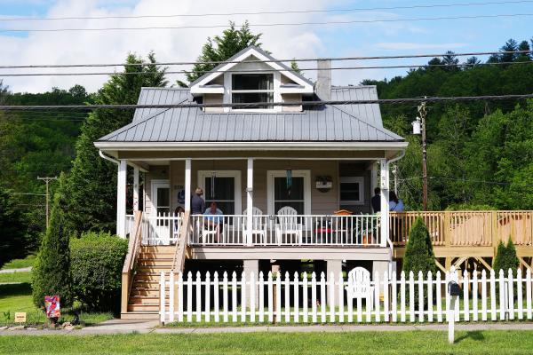 A single-story elevated house with a porch and door to the left and two windows to the right.