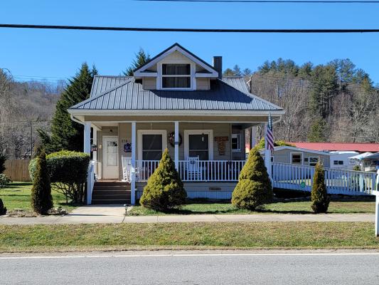 A single-story house at ground level with a porch and door to the left and two windows to the right.