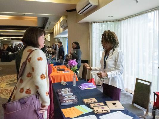 Woman at vendor table speaking to interested woman