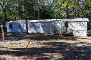 White mobile home with small wooden porch and children's toys in the yard