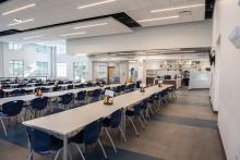 Inside dining hall with multiple long tables and chairs.