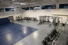 Large room that has several pieces of gym equipment, a blue mat and other workout machines/areas.