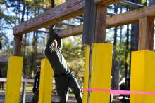 Person swinging on wooden monkey bars.