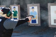 Female wearing protective ear covering shooting at a target downrange. 