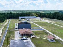 Overhead view of long field with two buildings and a parking lot on the side.