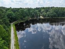 Lake with narrow path surrounding it. Trees boarder the lake area.