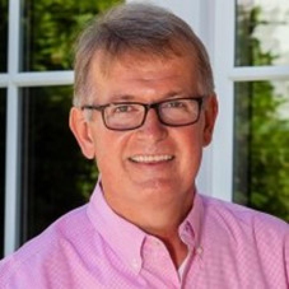 Picture of Stuart Mills in pink shirt with glasses