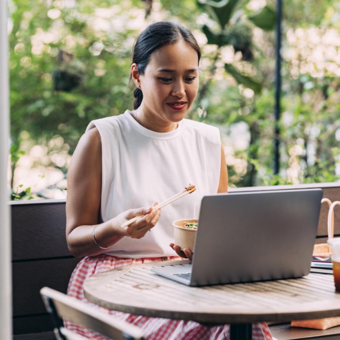 Woman enjoys lunch in front of laptop