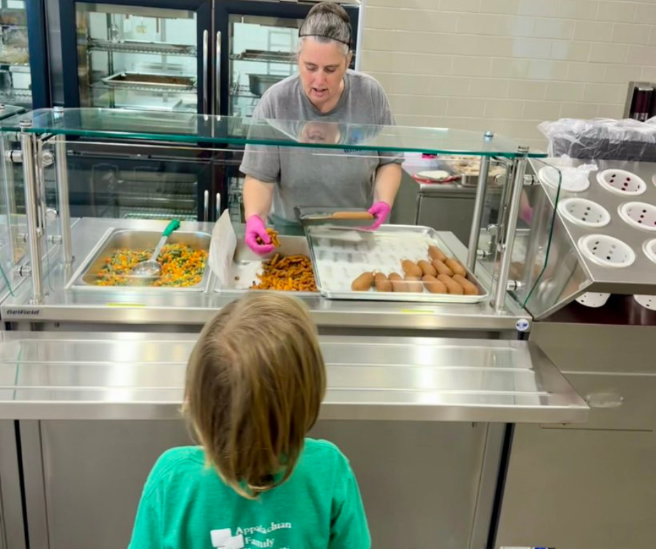 Elementary school nutrition staff serve lunch in a cafeteria line
