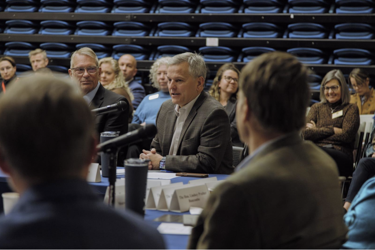 Leaders seated at tables with microphones