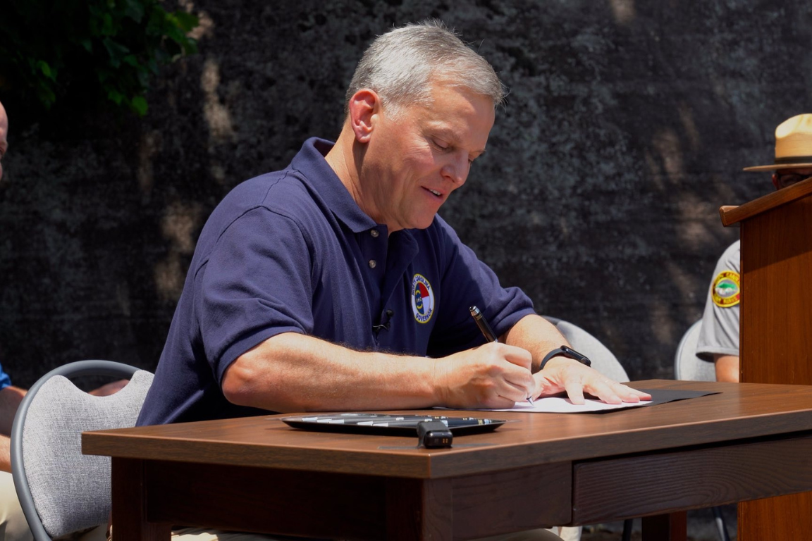 state leader signing a document in an outdoor setting