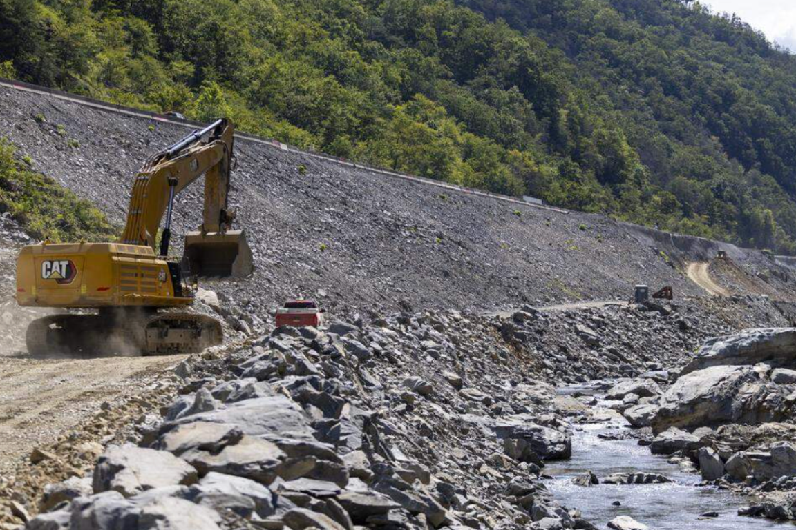 Heavy machinery moving earth near a roadway