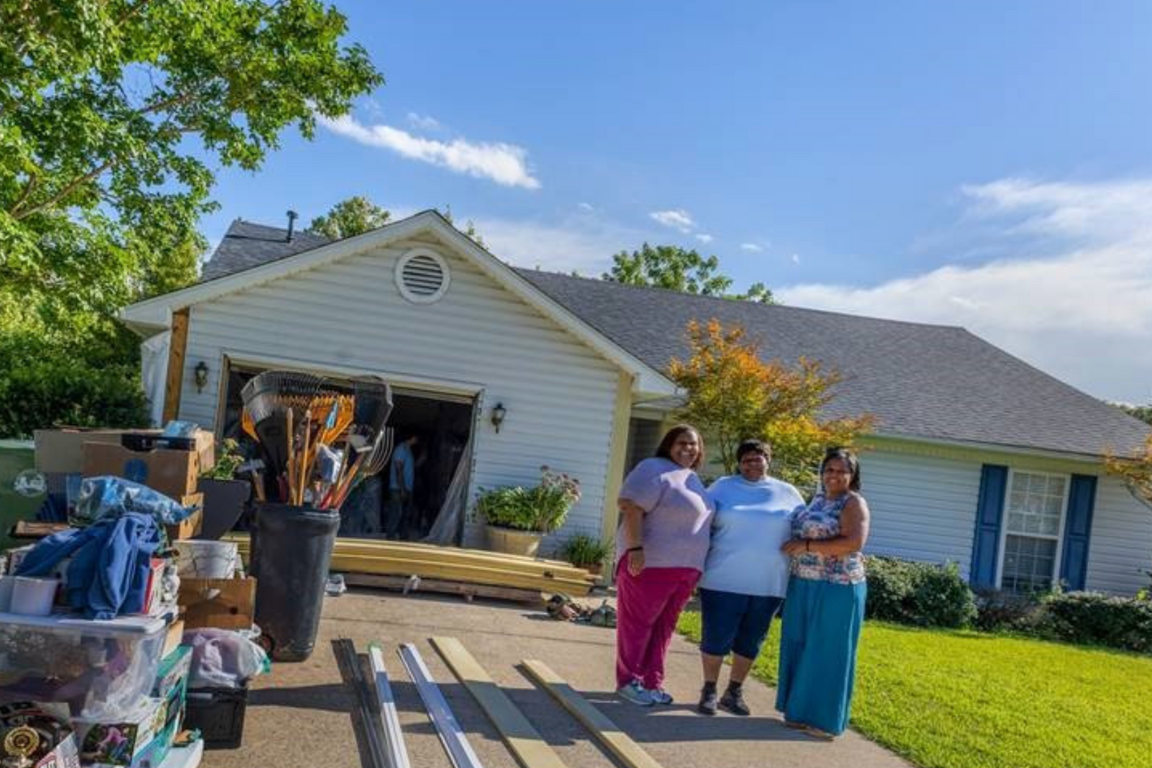 Family standing in front of a home receiving repairs