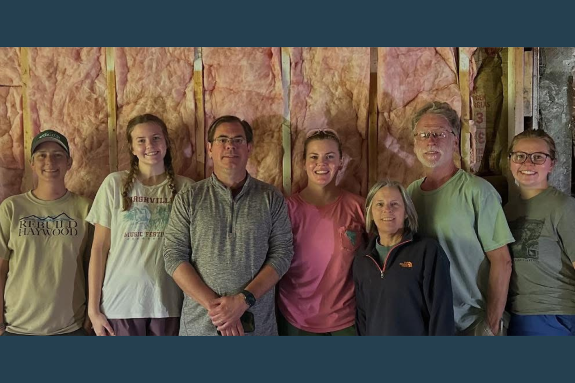 A group of volunteers pose in front of a home insulation project