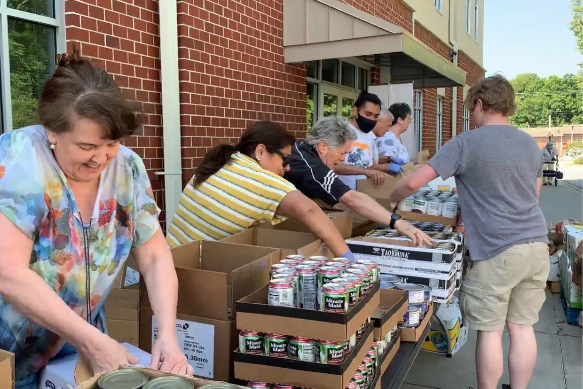 Volunteers organize food and distribute it to people in cars