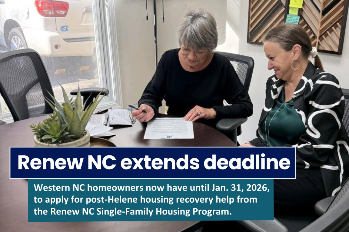 Two women sit at a table with paperwork