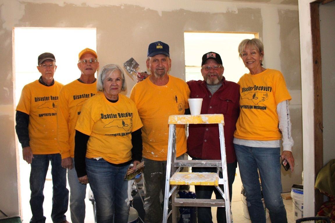 Six volunteers pose for a photo while performing a home construction project