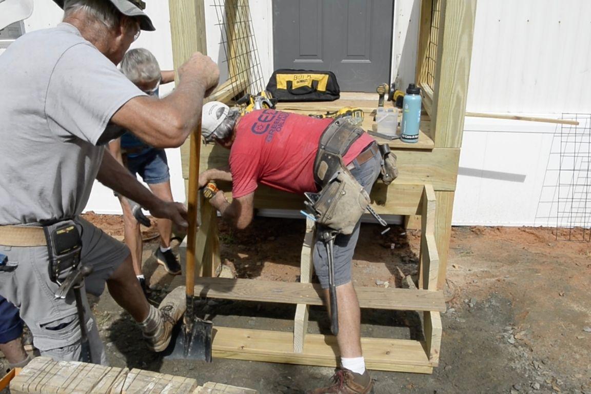 Workmen repairing entry steps to a damaged home