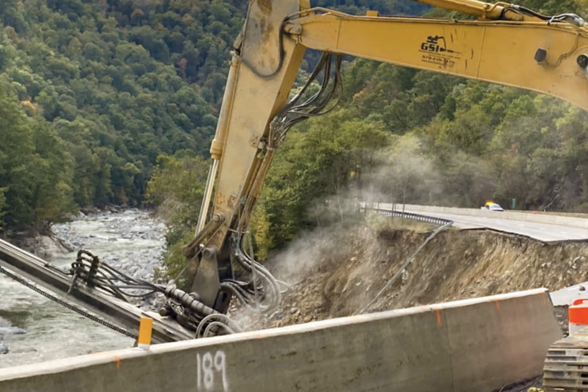 Construction equipment repairing infrastructure above a large gorge
