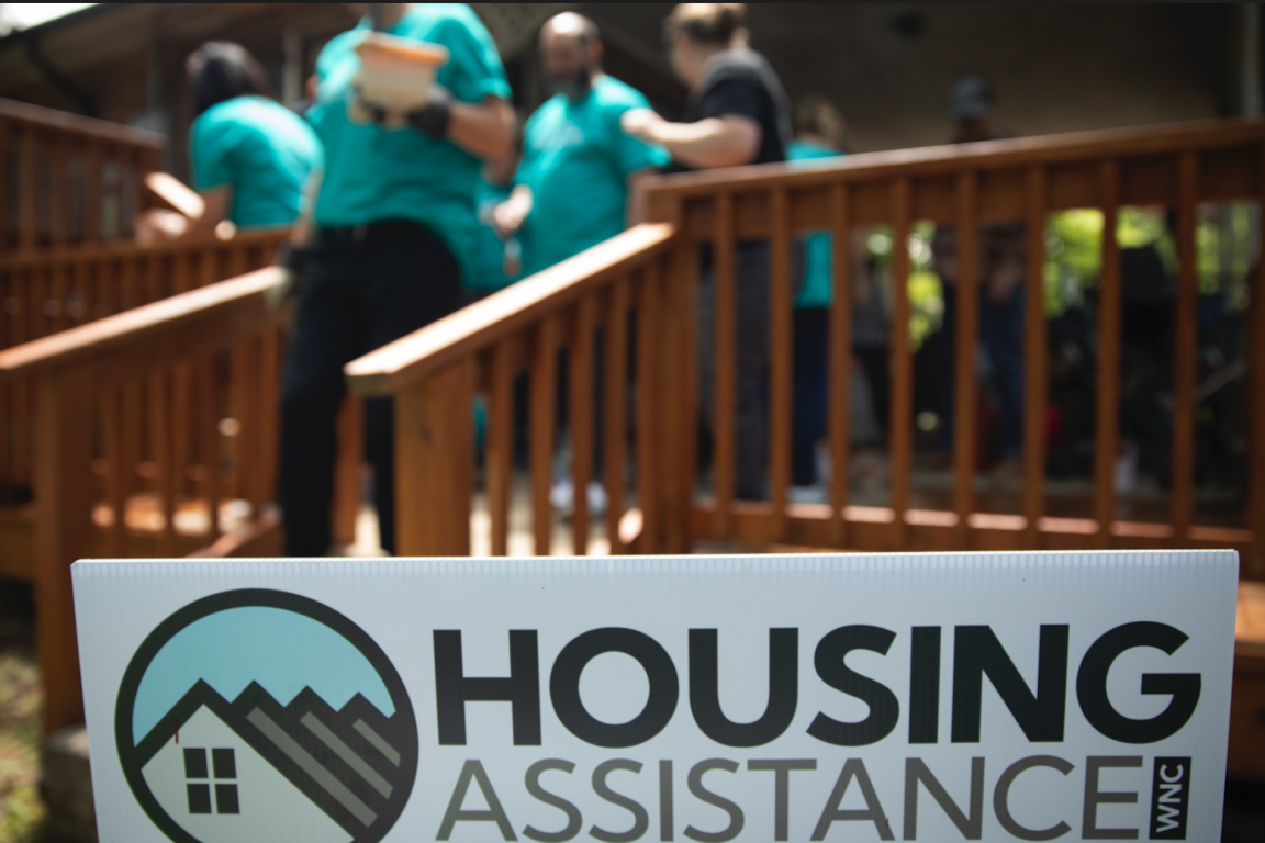 People dressed in teal tshirts gather on a home's porch
