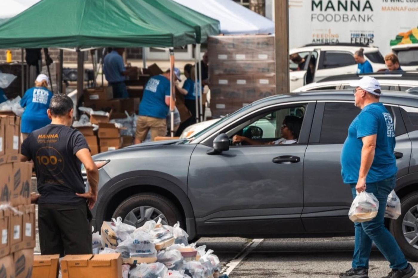 Volunteers organize food and distribute it to people in cars