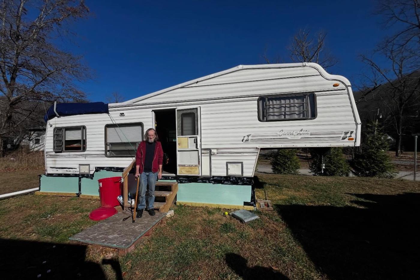 Man posed in front of travel trailer with green insulation installed
